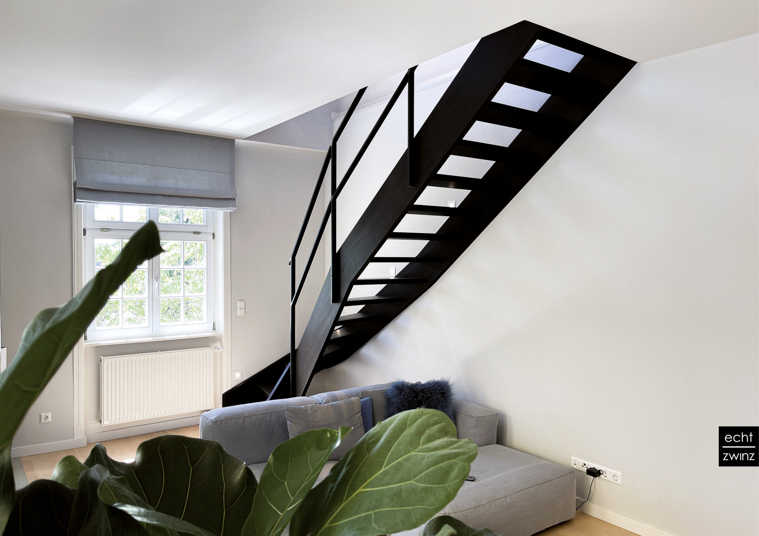 Schwarze Treppe mit Stufen und Wange aus Räuchereiche Handlauf aus Stahl, schwarz beschichtet