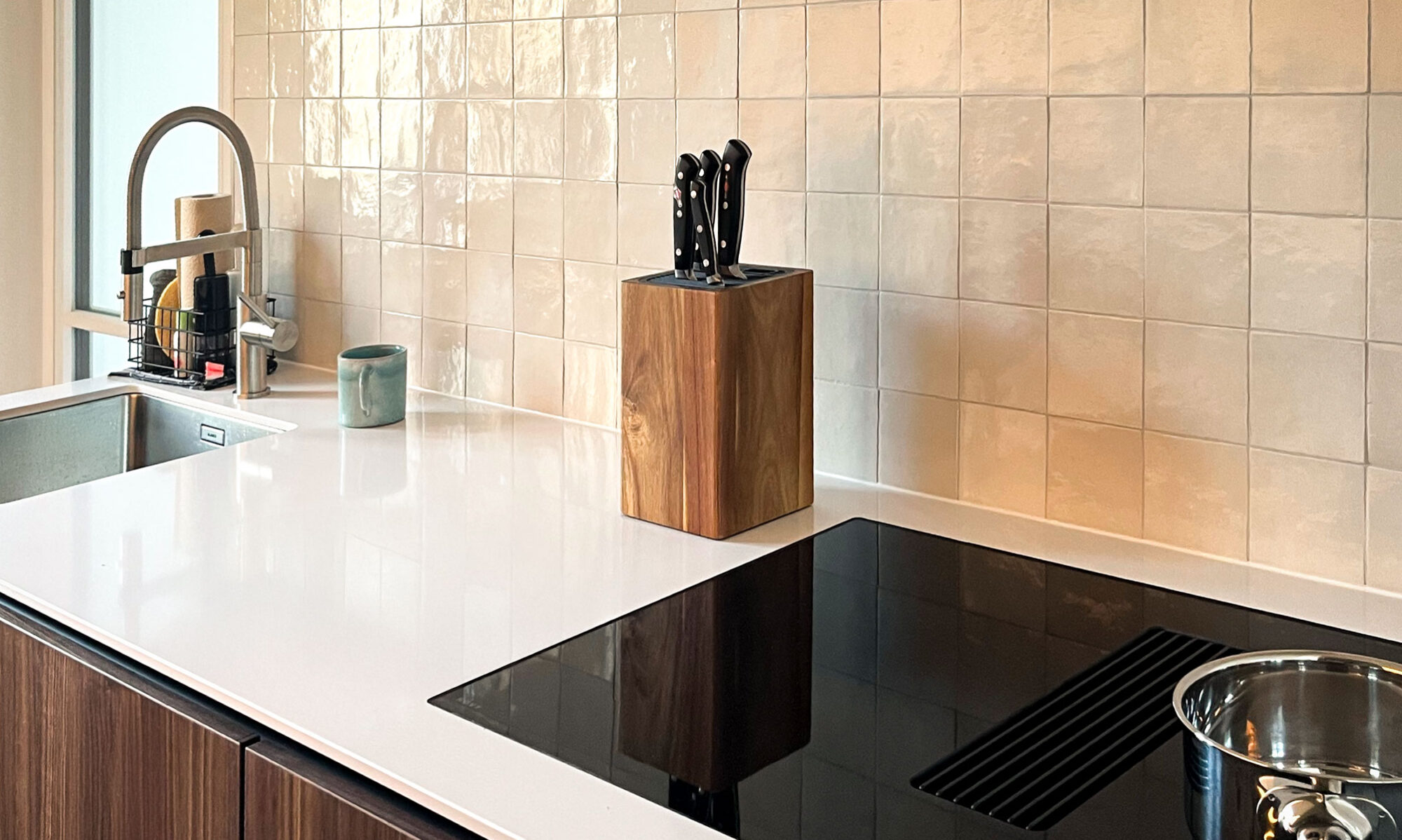 Designküche mit weißen Silestone-Flächen, handgeschöpften Fliesen und Nußbaumfronten in Stuttgart.