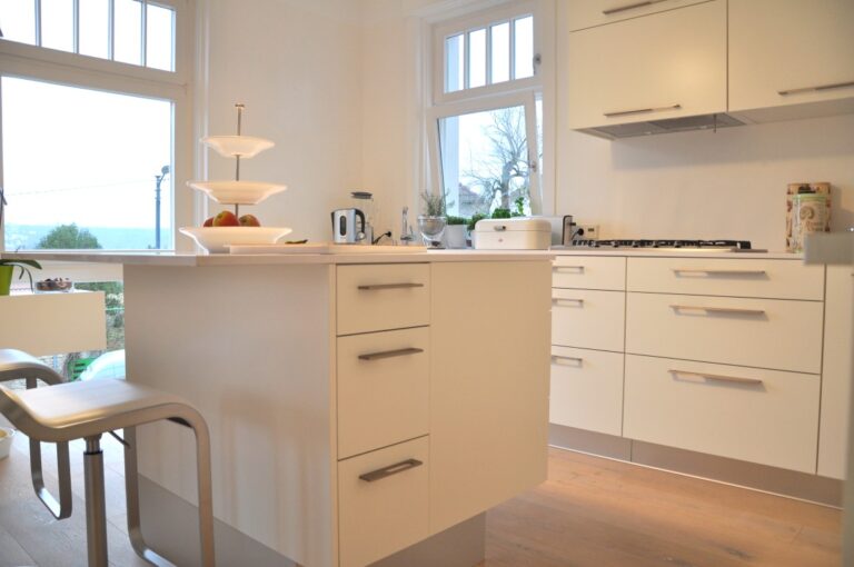 Küchen- und Hausumbau. Eine individuelle weiße Küche mit Kücheninsel und Frühstückstheke