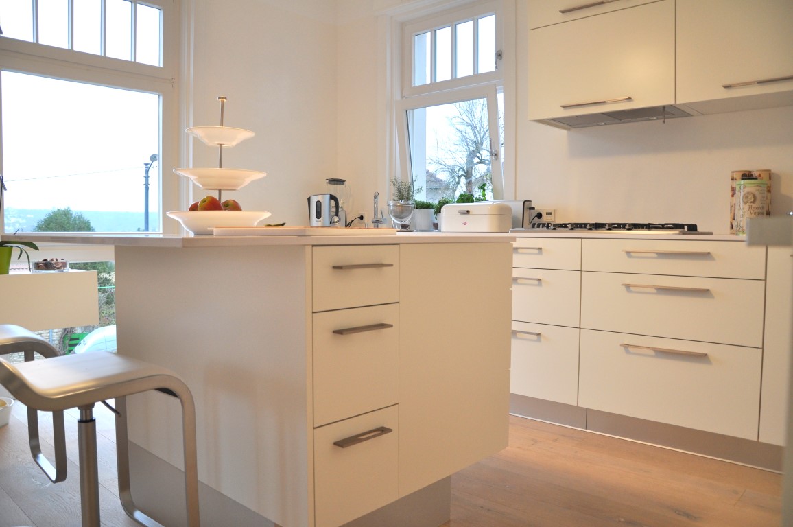 Küchen- und Hausumbau. Eine individuelle weiße Küche mit Kücheninsel und Frühstückstheke