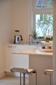 Küchen- und Hausumbau. Eine individuelle weiße Küche mit Kücheninsel und Frühstückstheke