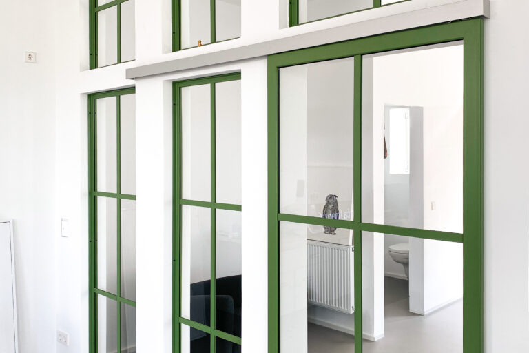 Grüner Stahl und Glas im authentischen Altbau