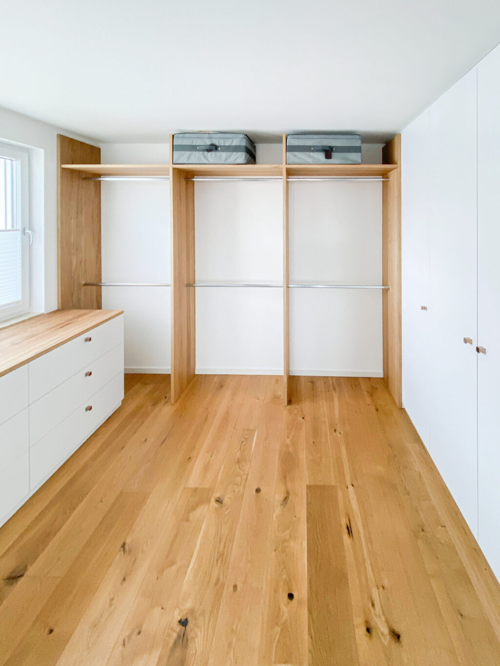 Ein Ankleide-Zimmer als begehbarer Kleiderschrank in Eiche mit viel Hängenden und weißen Einbauten