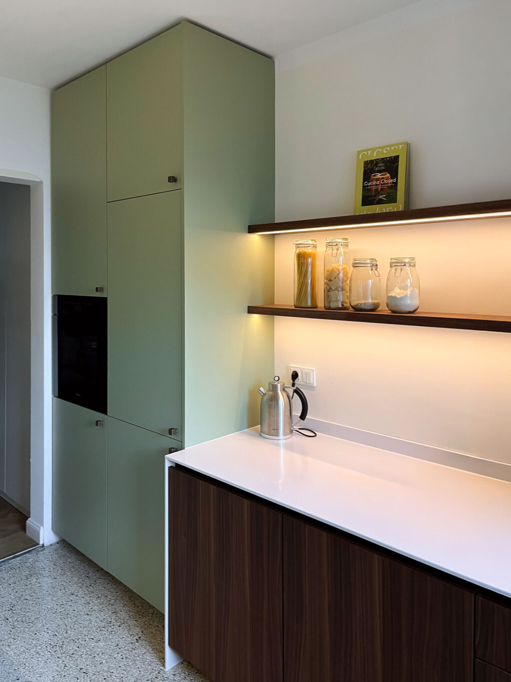 Wohnküche in Mint und Nußbaum mit LED-Regalborden, Silestone-Arbeitsplatte und klarer Linienführung.