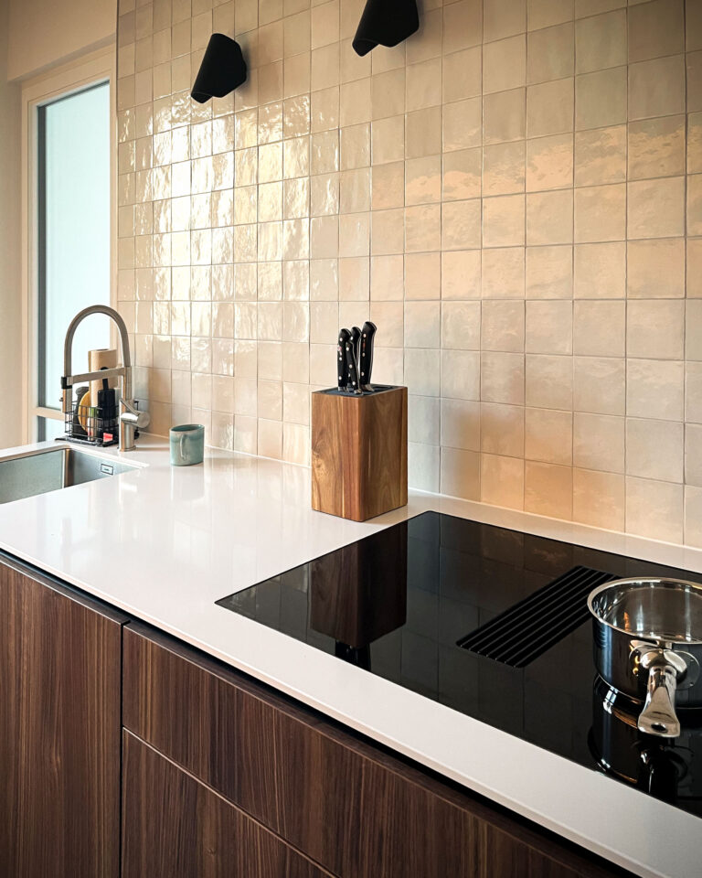 Designküche mit weißen Silestone-Flächen, handgeschöpften Fliesen und Nußbaumfronten in Stuttgart.