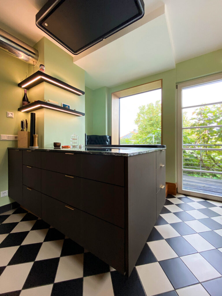 Küche mit gepolstertem Sitzfenster am schwarzen Eichentresen der Stein-Kochinsel mit Massivholzregalen und LED