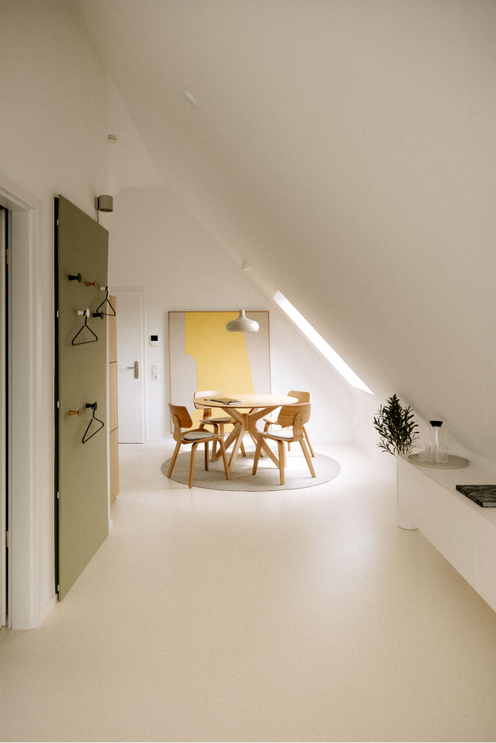 Der Esstisch steht angenehm und klar unterm Dachfenster im Tageslicht.