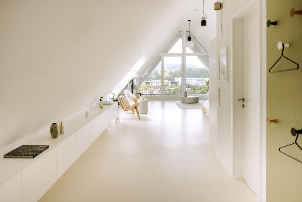 Das Sideboard entlang des Kniestocks und die flache Garderoben-Filzwand inszenieren die Flucht des langgezogenen Lofts.