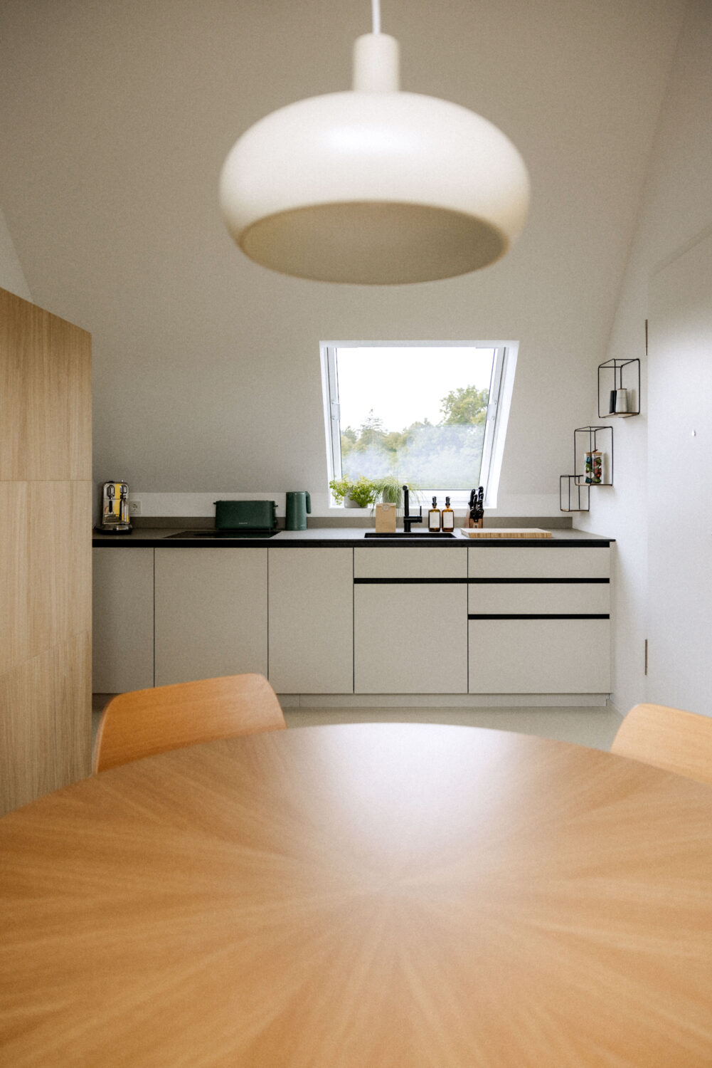 Die Küchenzeile ist so eingeteilt, dass unterm hellen Fenster Spülbecken und Schneidebrett liegen. Geräte und Herd sind dezent eingelassen oder hinter den Fronten versteckt.