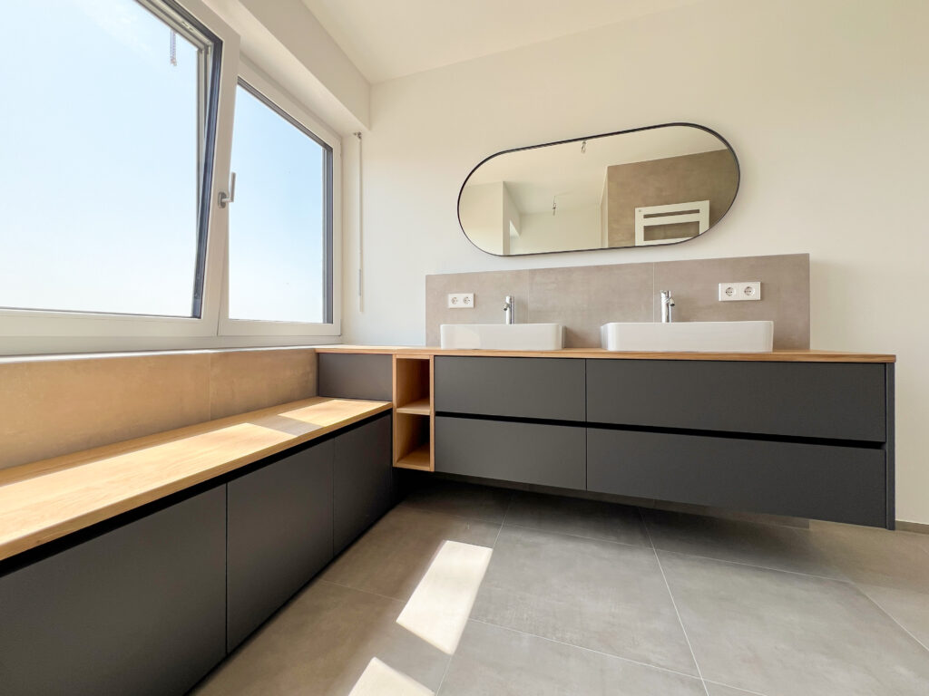 Badezimmer mit Sitzbank und großem Spiegel – Rückzugsort mit Panorama und viel Licht.