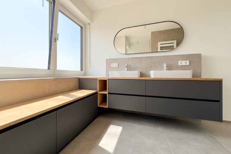Badezimmer mit Sitzbank und großem Spiegel – Rückzugsort mit Panorama und viel Licht.