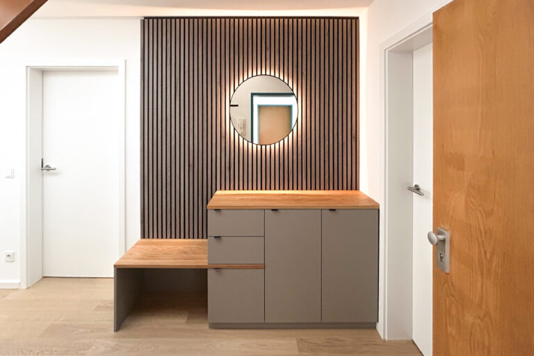 Garderobe mit rundem Spiegel und Akustikpaneel aus Holz – Sideboard mit Schubladen und indirekter LED-Beleuchtung.