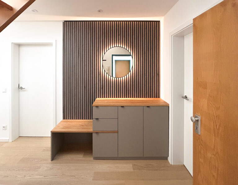 Garderobe mit rundem Spiegel und Akustikpaneel aus Holz – Sideboard mit Schubladen und indirekter LED-Beleuchtung.