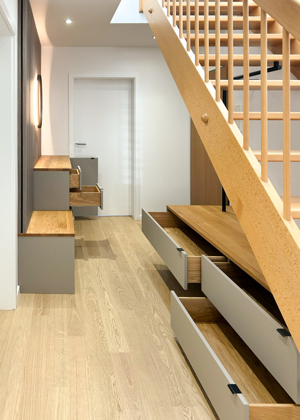 Garderobe unter der Treppe mit großzügigem Stauraum und maßgefertigten Eichenschubladen – funktionale Flurlösung mit Sitzbank, Schubladen aus Massivholz und optimal genutztem Raum im Eingangsbereich.
