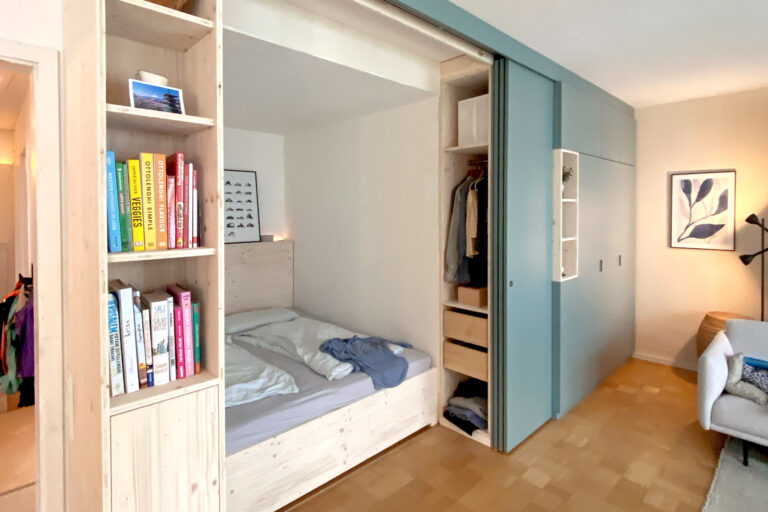 Eine Bettnische im Wohnzimmer versteckt hinter Schiebetüren