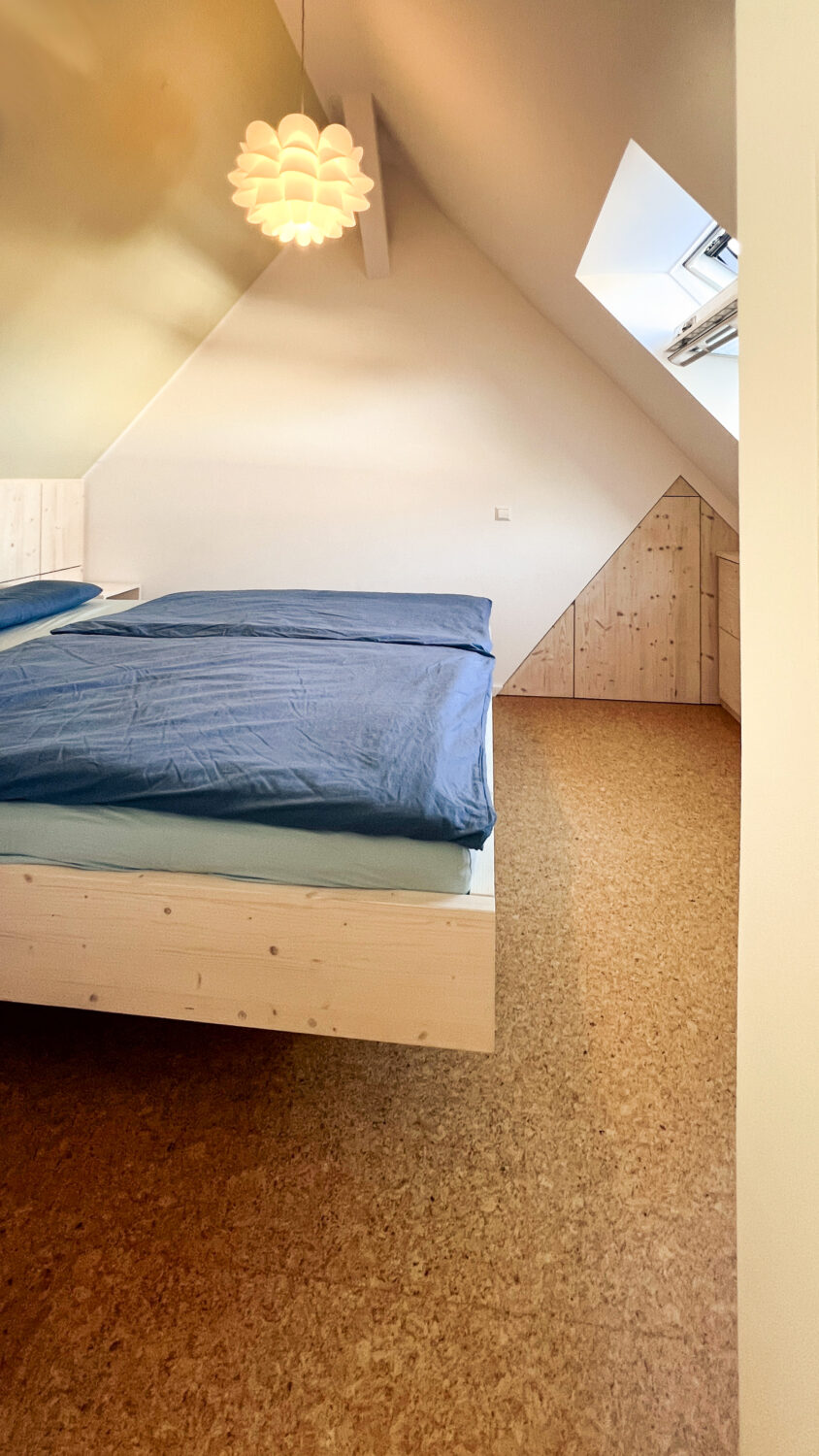 Die Drehtür in der Wand nimmt die Raumgeometrie der Schräge auf und bietet hinter der Wand noch weiteren Staurraum für Saisonbettwäsche, -kleidung und mehr.